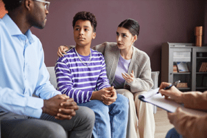 a teen and parent talk to a therapist in a family systems therapy program