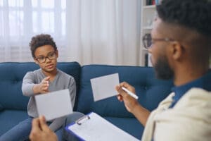 an adolescent boy lokos at flash cards with a therapist in a cognitive-behavioral therapy program