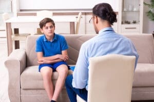 an adolescent boy listens to a therapist during dialectical behavior therapy